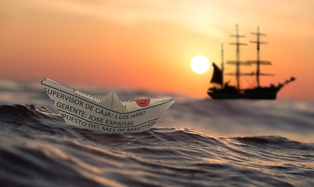 夕暮れの海に浮かぶ紙で作った船