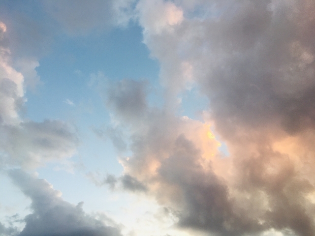 冷たく温かい色の雲が浮かぶ夕暮れ時の空