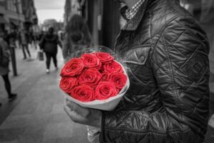愛する気持ち分の赤いバラの花束を持つ男性