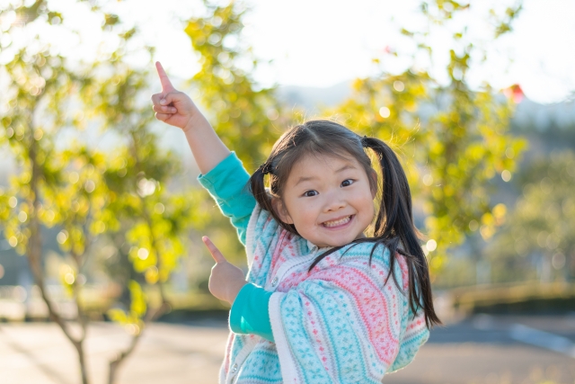 明るく空を指さす少女