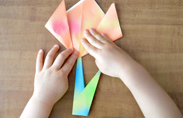 折り紙で楽しく遊ぶ幼児の手